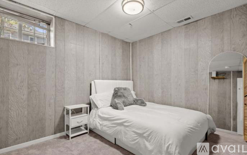 A bedroom with a white bed and a small white nightstand.