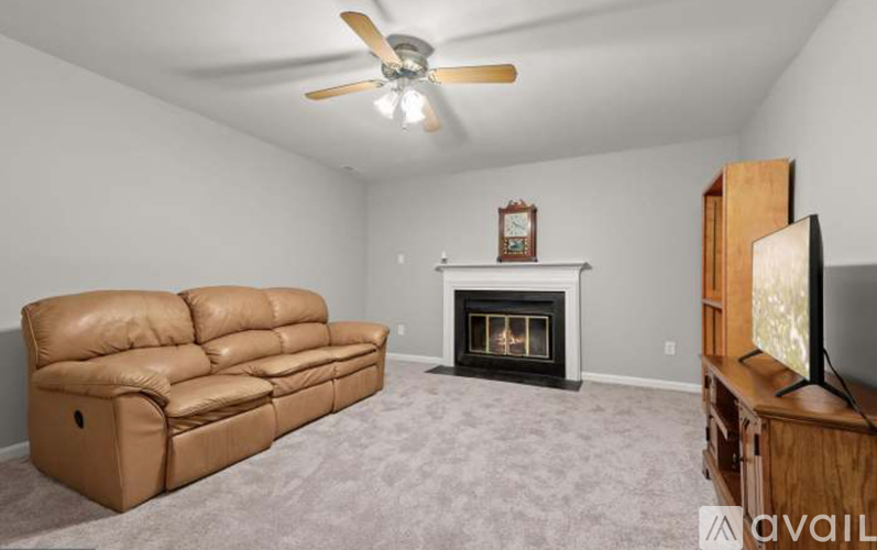 A living room with a brown leather couch, a fireplace, and a television.