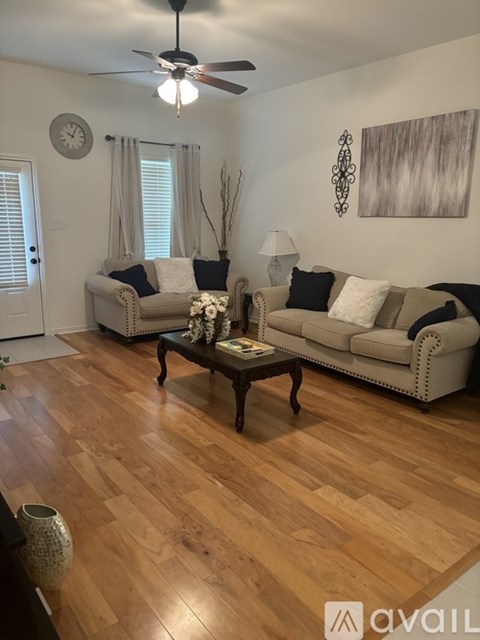 A living room with a white couch and a wooden floor.