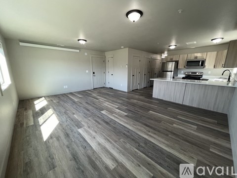 A spacious room with wooden flooring and a kitchen area with a sink and stove.