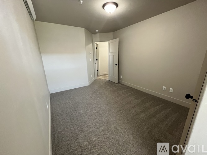 A spacious room with carpeted floor and a door at the end.