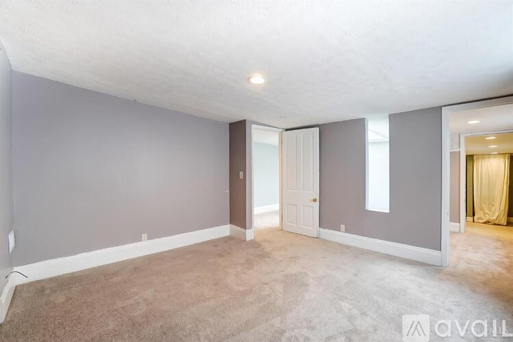 A spacious room with a carpeted floor and a door leading to another room.