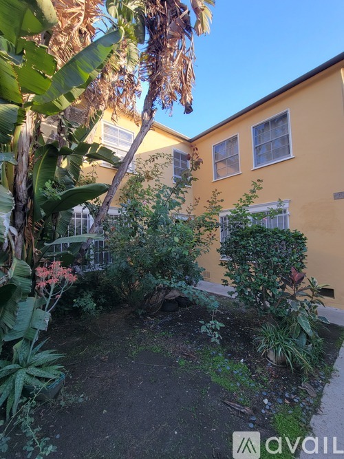 A yellow building with a garden in front.