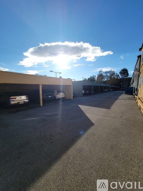 A sunny day at the parking lot with cars parked and a building in the background.