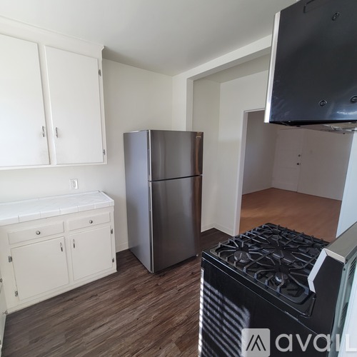 A kitchen with white cabinets and a stainless steel refrigerator.