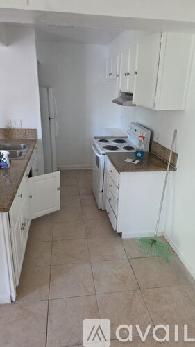 A kitchen with white cabinets and a tiled floor.