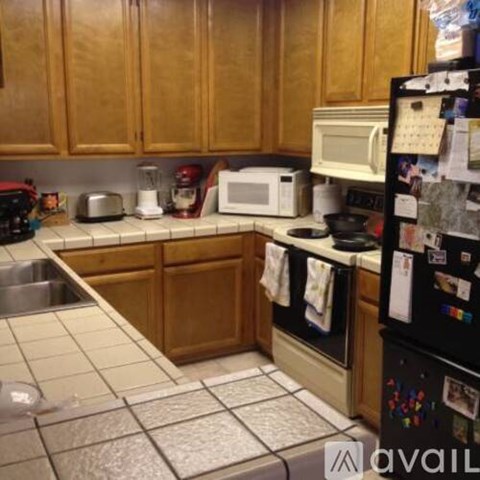 A kitchen with wooden cabinets and a black fridge.