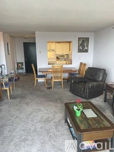 A living room with a grey carpet and a wooden coffee table.