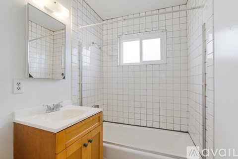 A bathroom with a white sink and a white tiled shower.