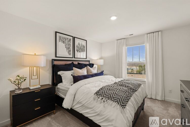 A bedroom with a large bed, a nightstand with a lamp, and two framed pictures on the wall.