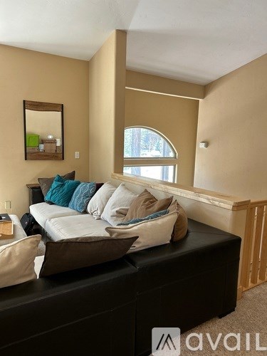 A living room with a black couch and a mirror on the wall.