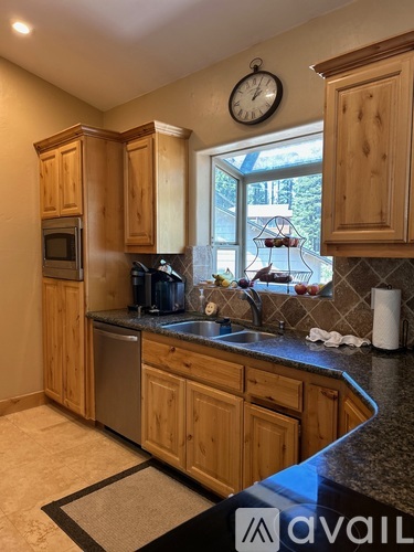 A kitchen with wooden cabinets and a clock on the wall.