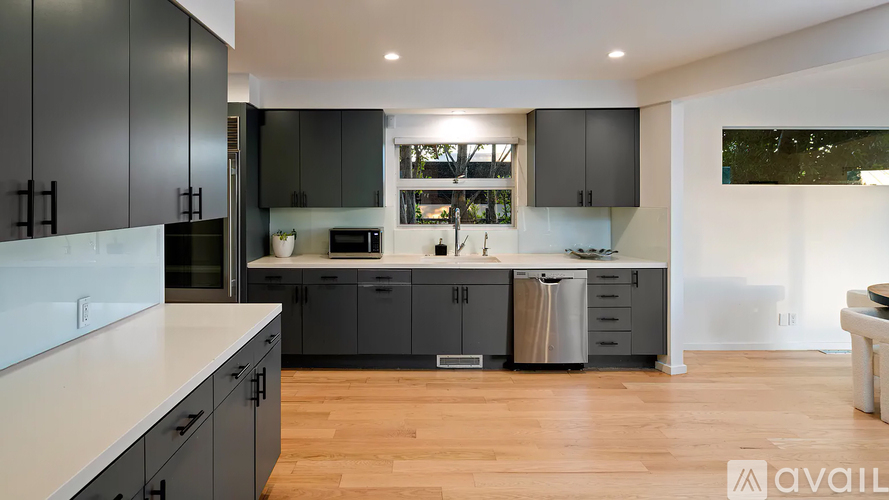 A modern kitchen with dark grey cabinets and a white countertop.