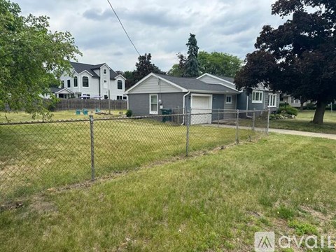 A house with a grey roof is behind a fence.