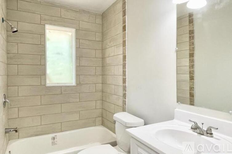 A bathroom with a white tub, sink, and toilet.
