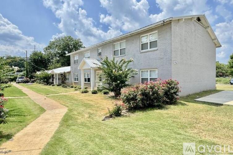 A residential building with a well-maintained lawn and a clear sky.