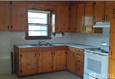 A kitchen with wooden cabinets and a white stove top oven.