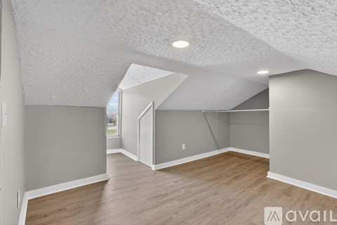 A spacious room with wooden flooring and white walls.