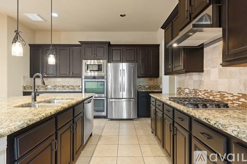 A kitchen with dark brown cabinets and a granite countertop.