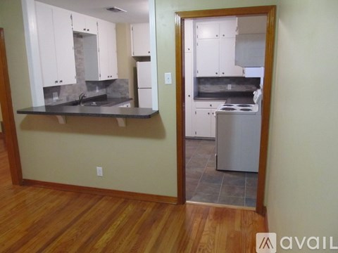 A kitchen with white cabinets and a wooden floor.