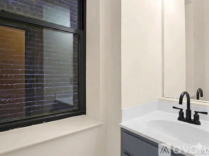 A modern bathroom with a white sink and a window with a brick pattern.