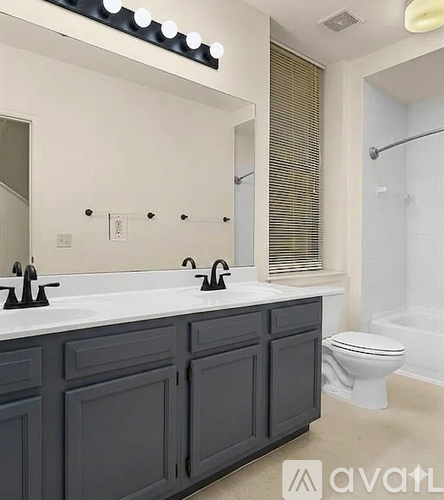 A bathroom with a white countertop and a black cabinet.
