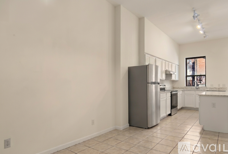 A kitchen with white cabinets and appliances in a white room.
