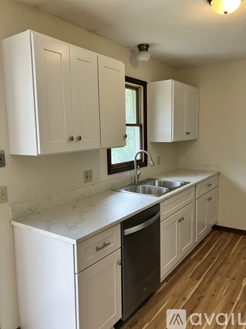 A kitchen with white cabinets and a marble countertop.