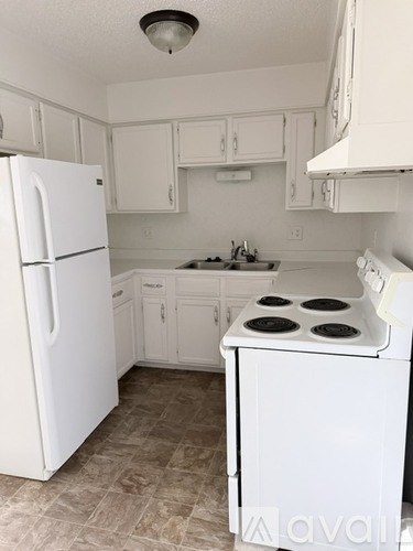 A white kitchen with a stove and refrigerator.