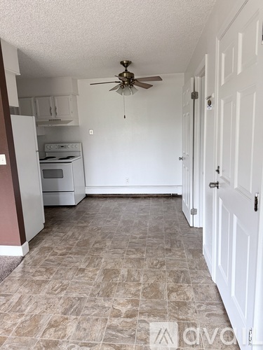 A kitchen with a fan on the ceiling and a tiled floor.
