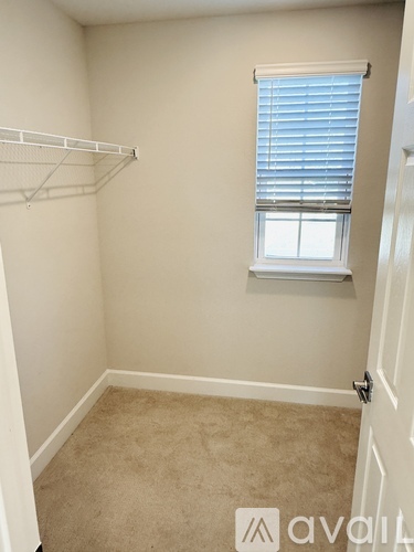 A small bedroom with a carpeted floor and a window with blinds.
