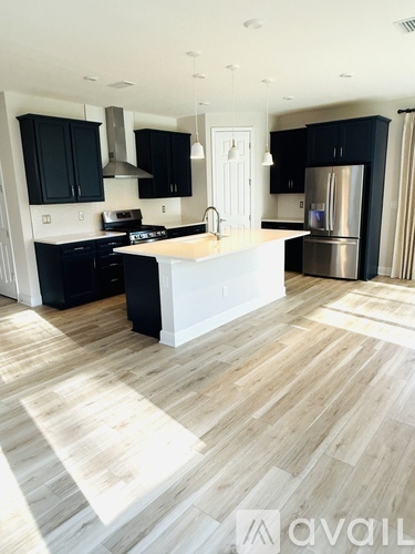 A kitchen with black cabinets and a white island.