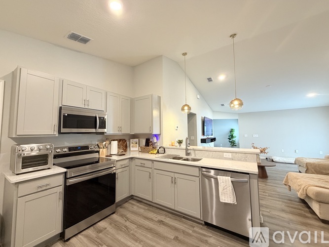 A modern kitchen with stainless steel appliances and a wooden floor.