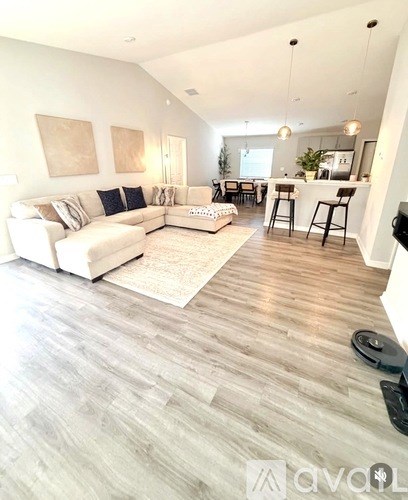 A spacious living room with a white sofa and a bar area.