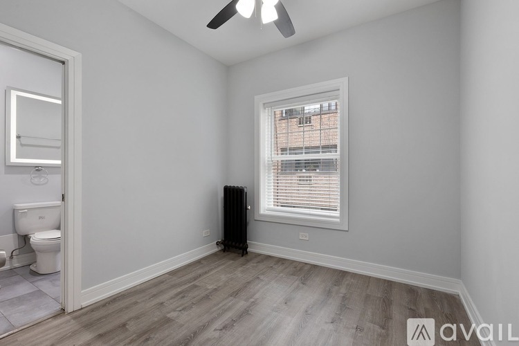 A room with a toilet, a window with blinds, and a ceiling fan.
