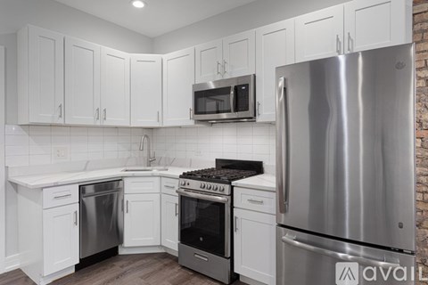 A kitchen with white cabinets and a stainless steel refrigerator.