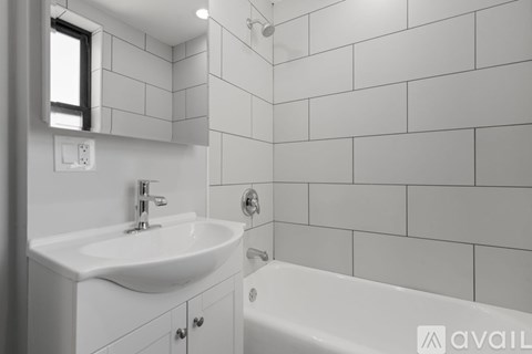 A white bathroom with a sink, mirror, and bathtub.