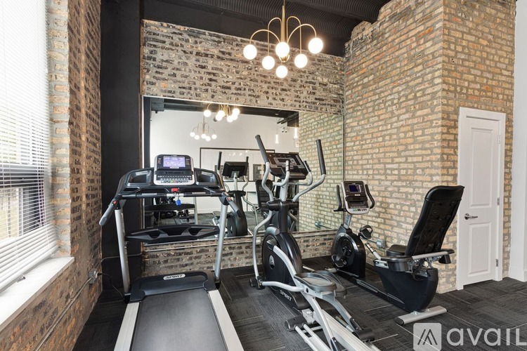 A gym with a brick wall and a treadmill, exercise bike, and weights.