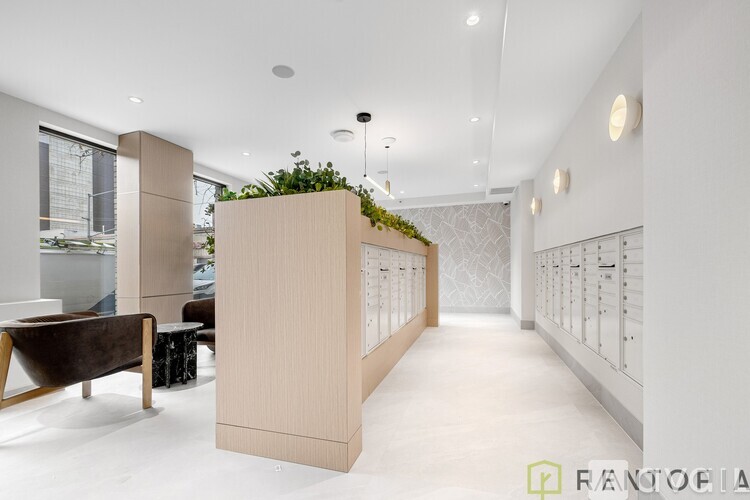 A modern interior space with a long hallway, a bench, and a green plant on a wall.
