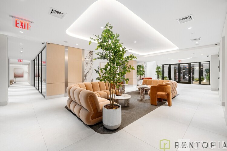 A modern office lobby with a tree in a planter, a couch, and chairs.