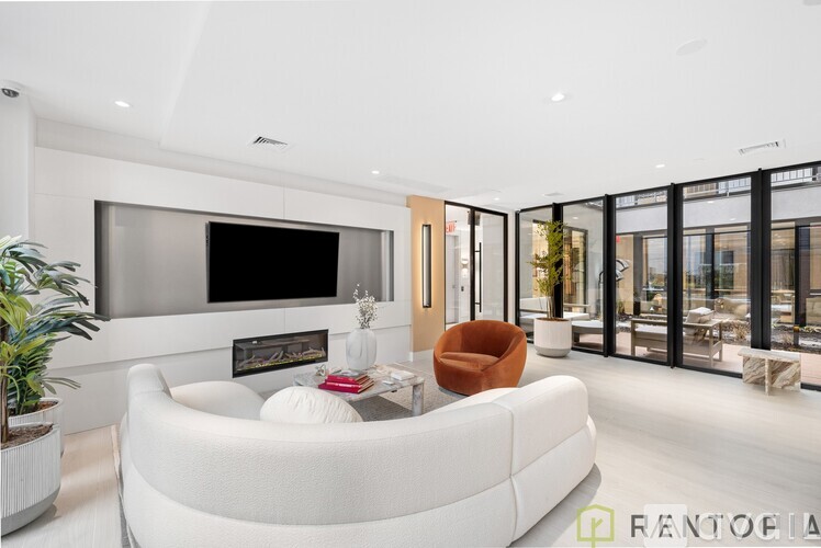 A modern living room with a white sofa and a flat screen TV mounted on the wall.