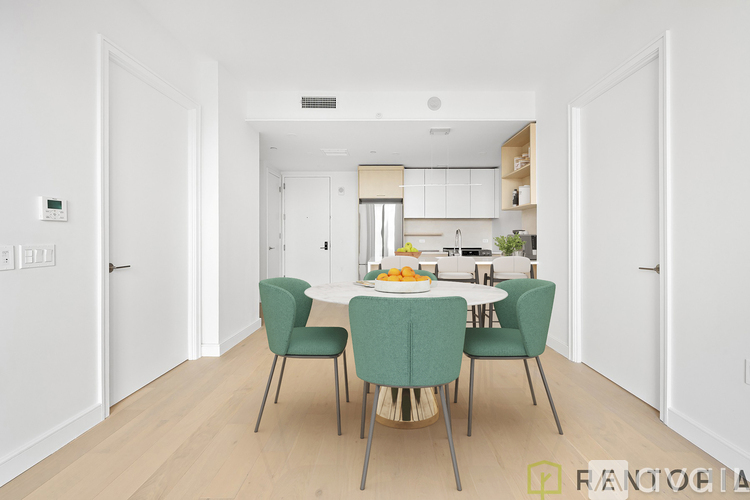 A dining room with a table set for two and a kitchen in the background.