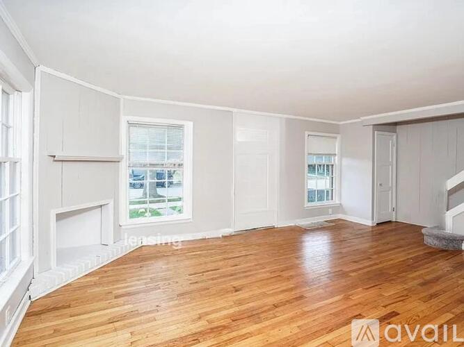 A spacious room with wooden floors and white walls.