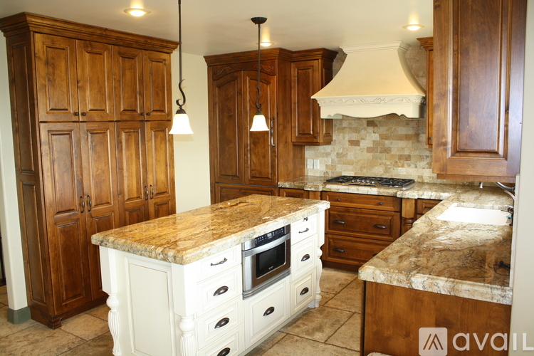 A kitchen with wooden cabinets and a marble countertop.