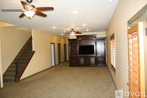A living room with a brown carpet and a wooden entertainment center.