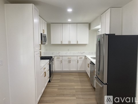 A kitchen with white cabinets and a black refrigerator.