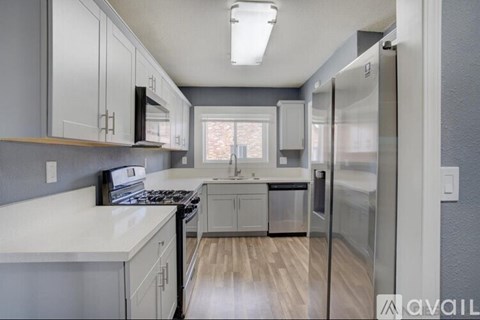 A kitchen with white countertops and stainless steel appliances.