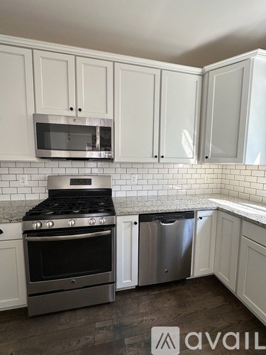 A kitchen with white cabinets and a stainless steel oven and microwave.