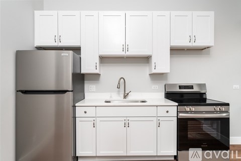 A kitchen with white cabinets and appliances including a refrigerator, sink, and oven.