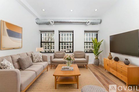 A living room with a grey couch, a wooden coffee table, a brown side table, a flat screen TV, and a painting on the wall.